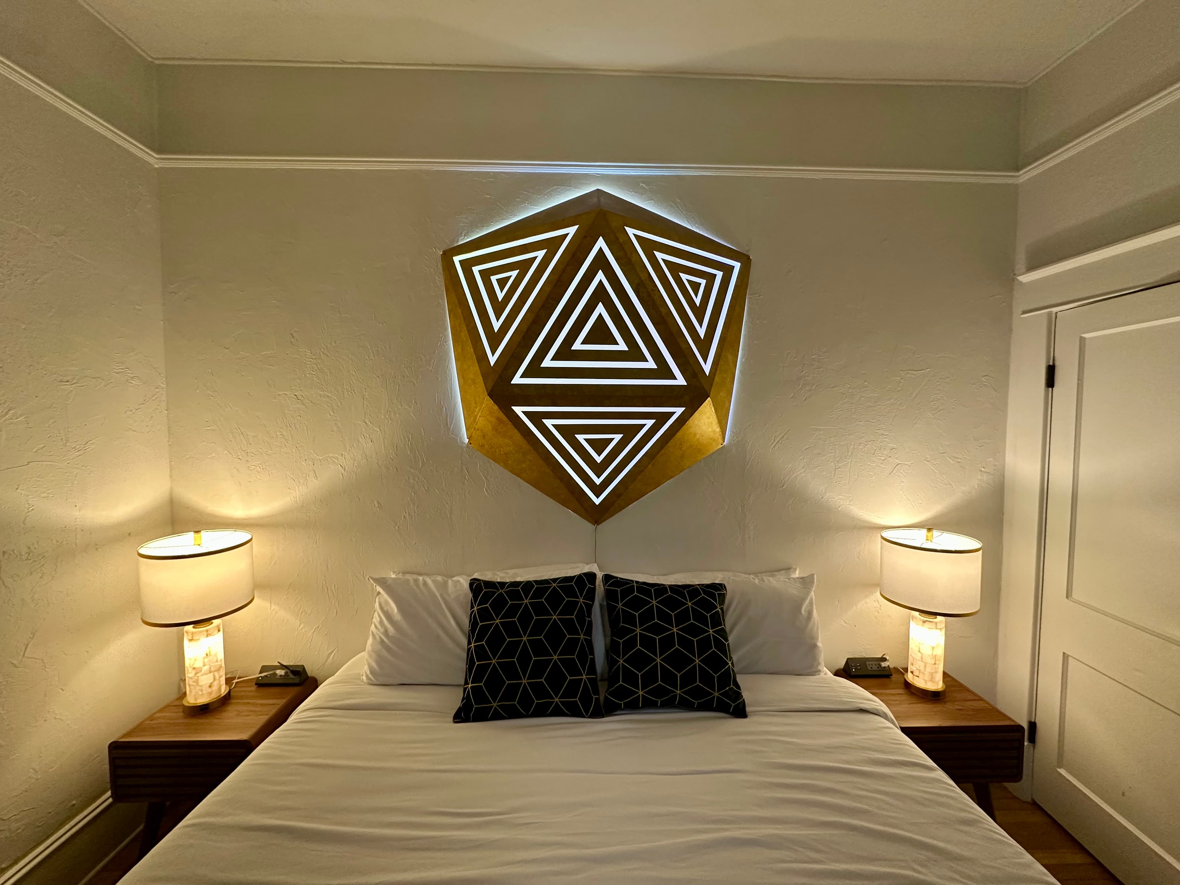 Gold faceted hexagonal LED headboard panel with glowing white triangle inlays above a bed