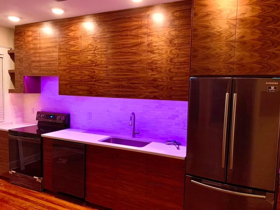 Backlit hardwood media wall with integrated LED wash, reading as one composition