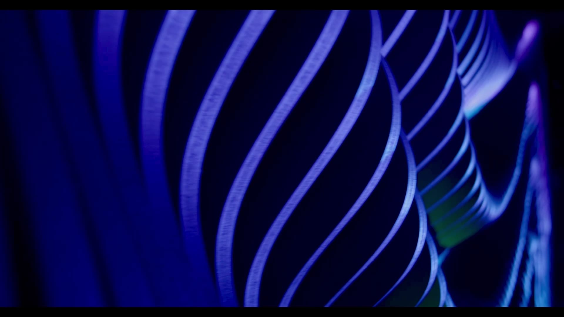 Iridescent projection light sweeping across a contoured parametric rib wall