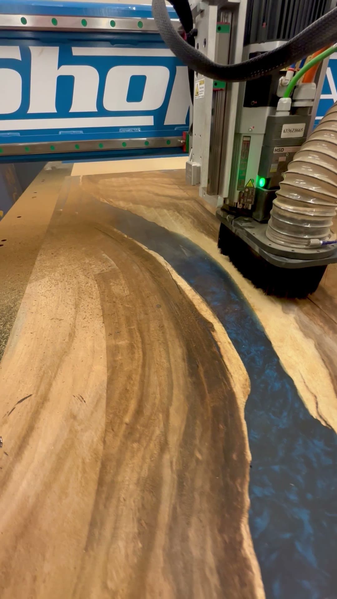 The ShopSabre machining a hardwood desk panel, chips lifting off the cut